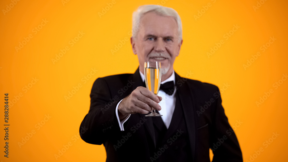 Gray-haired man in suit toasting with champagne glass, celebrating life, holiday Gray-haired man in suit toasting with champagne glass, celebrating life, holiday