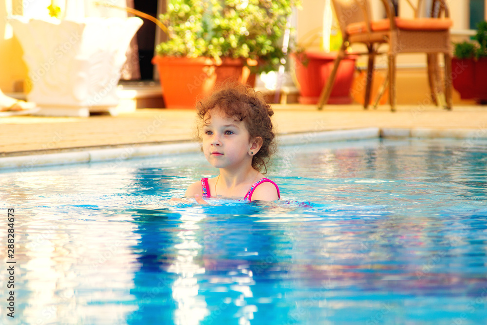 Accommodation in a small hotel on the Greek islands. little girl in the pool at a sunny summer day. Travel concept