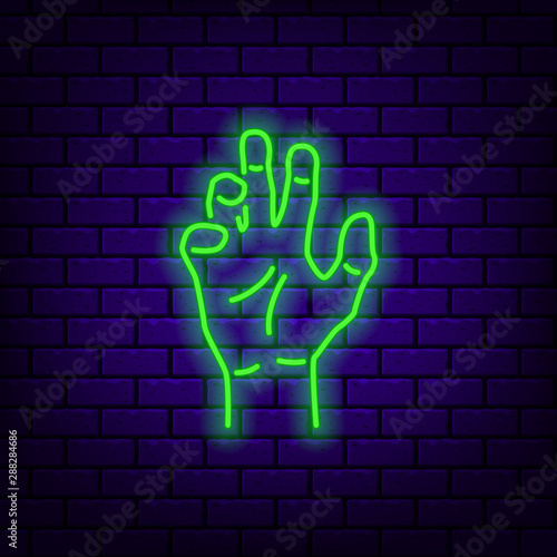 Neon zombie hand icon on dark brick background.