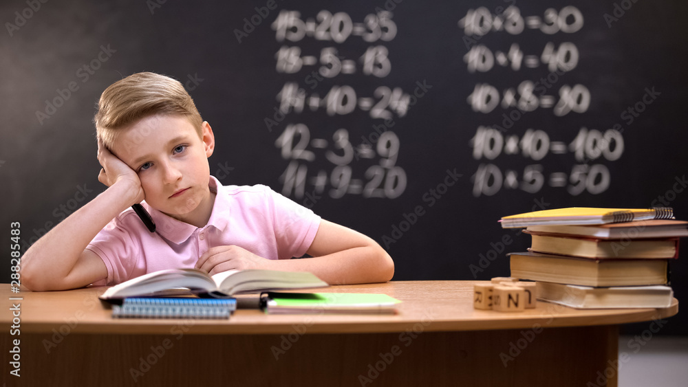 Overloaded schoolboy sitting at desk and failing to solve difficult equation Overloaded schoolboy sitting at desk and failing to solve difficult equation