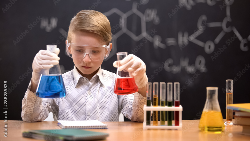 Little nerd comparing colorful liquids in flasks watching reaction, chemistry Little nerd comparing colorful liquids in flasks watching reaction, chemistry
