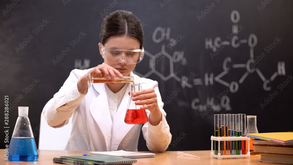 Chemistry student mixing liquids in scientific laboratory, conducting experiment Chemistry student mixing liquids in scientific laboratory, conducting experiment
