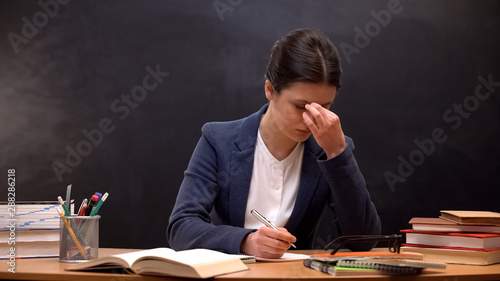 Bilde på lerret Lady teacher checking assignments and rubbing eyes, feeling tension and migraine