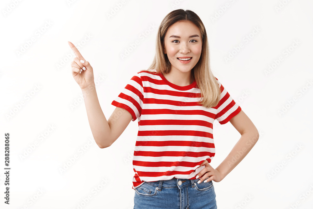Girl shocked you never seen it. Charismatic good-looking asian blond woman pointing upper left corner smiling pleased hold hand waist confident, satisfied pose standing white background Girl shocked you never seen it. Charismatic good-looking asian blond woman pointing upper left corner smiling pleased hold hand waist confident, satisfied pose standing white background