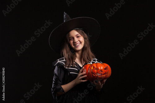Little girl in a witch costume doing witchcraft on a scary pumpkin
