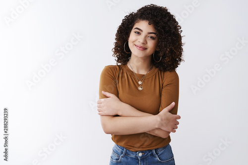 Tender attractive young alluring curly-haired nice girl smiling feel warmth care hugging herself standing comfort grinning joyfully enjoying relaxing romantic moment, white background