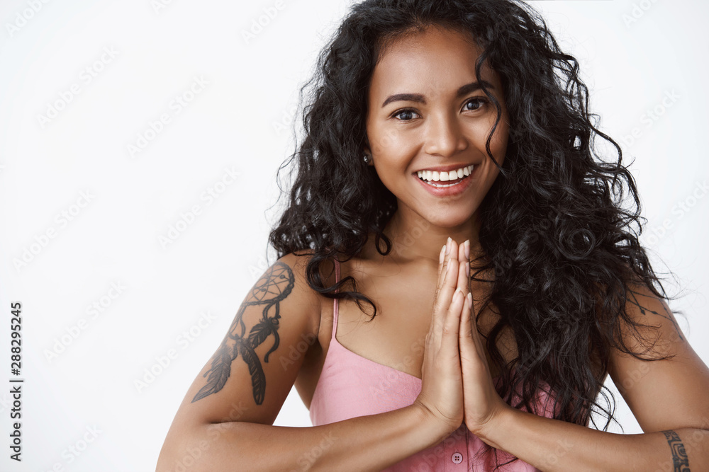 Wellbeing, emotions and happiness concept. Attractive friendly african-american curly-haired woman with tattoos, press hands together in pray, saying namaste as do yoga, white background Wellbeing, emotions and happiness concept. Attractive friendly african-american curly-haired woman with tattoos, press hands together in pray, saying namaste as do yoga, white background