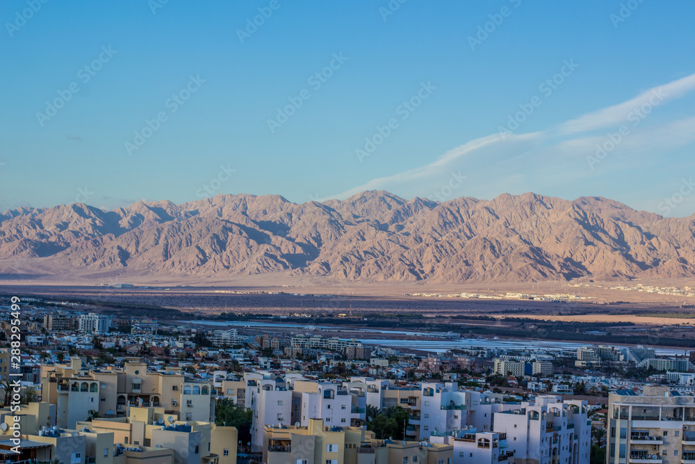 Israeli city Eilat top view from drone with living houses foreground and desert mountain ridge Middle East scenery landscape background 