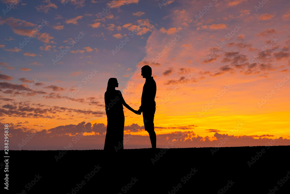 Silhouettes of couple hold hand together ,romantic man and woman against the sunset sky. Valentine theme and vintage photo.