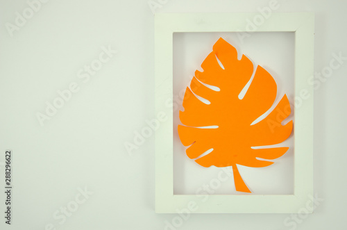 Flat lay orange paper monstrea palm leaf in a white plastic frame. Summer mockup photo