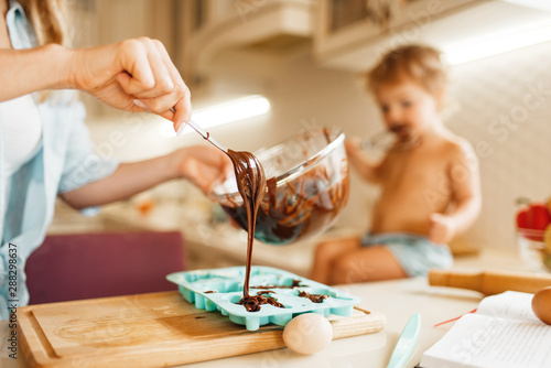 Mother and kid cooking and tastes melted chocolate