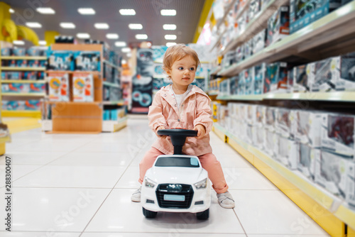 Little girl on electromobile in kids store photo