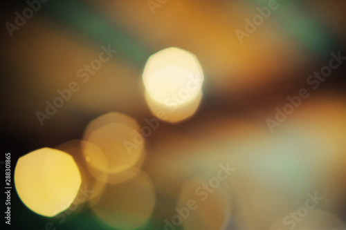 Blurred subtle bokeh with sparkling golden and green light. Abstract background. © Romanova