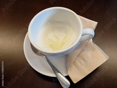 Out of the hot green tea cup set with tissue on drak brown wood background.