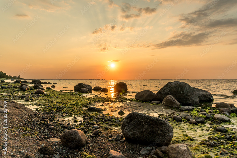Beautiful sunset at the beach of the baltic sea with boulders in the forground