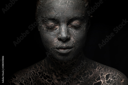 portrait of a woman with cracked black clay