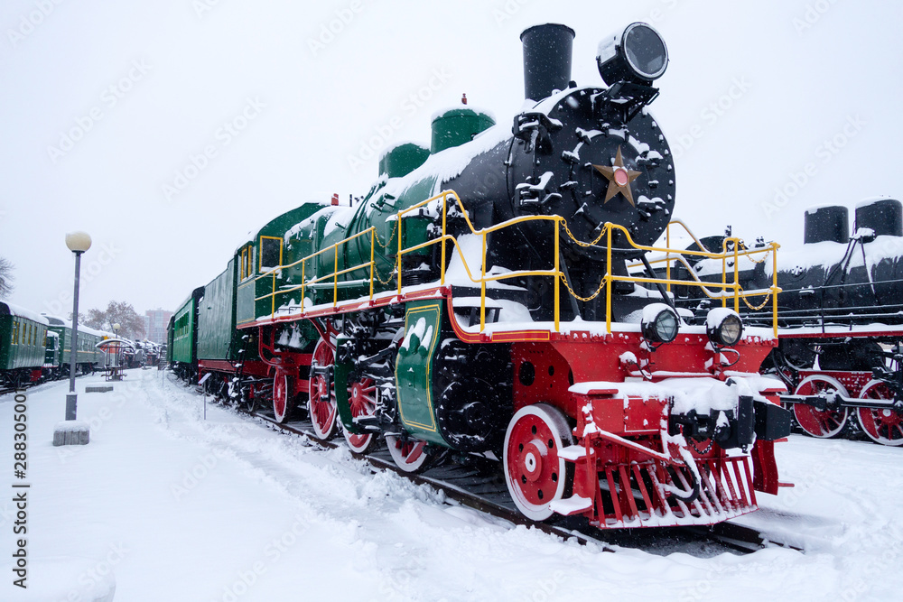 Fototapeta premium Steam train in snow. Soviet black and red locomotive. Steam engine transport.