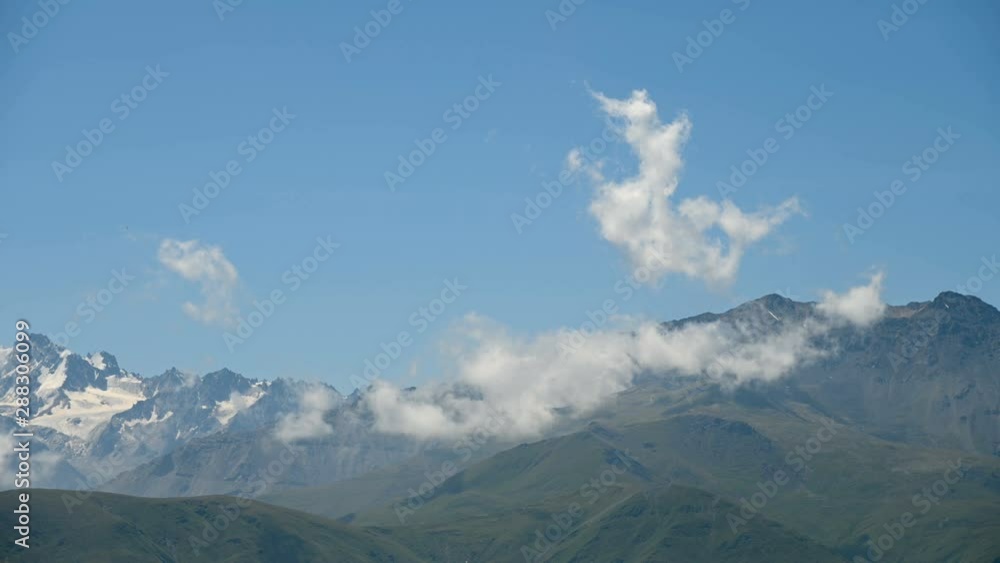 Daytime time lapse of the highlands. Skyline with snowy mountain peaks on a summer sunny day. Concept of weather change and cloud formation. Daytime time lapse of the highlands. Skyline with snowy mountain peaks on a summer sunny day. Concept of weather change and cloud formation.