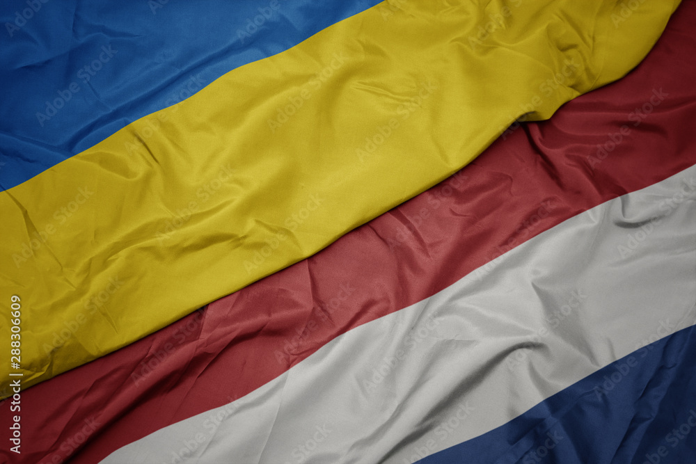 waving colorful flag of netherlands and national flag of ukraine. waving colorful flag of netherlands and national flag of ukraine.