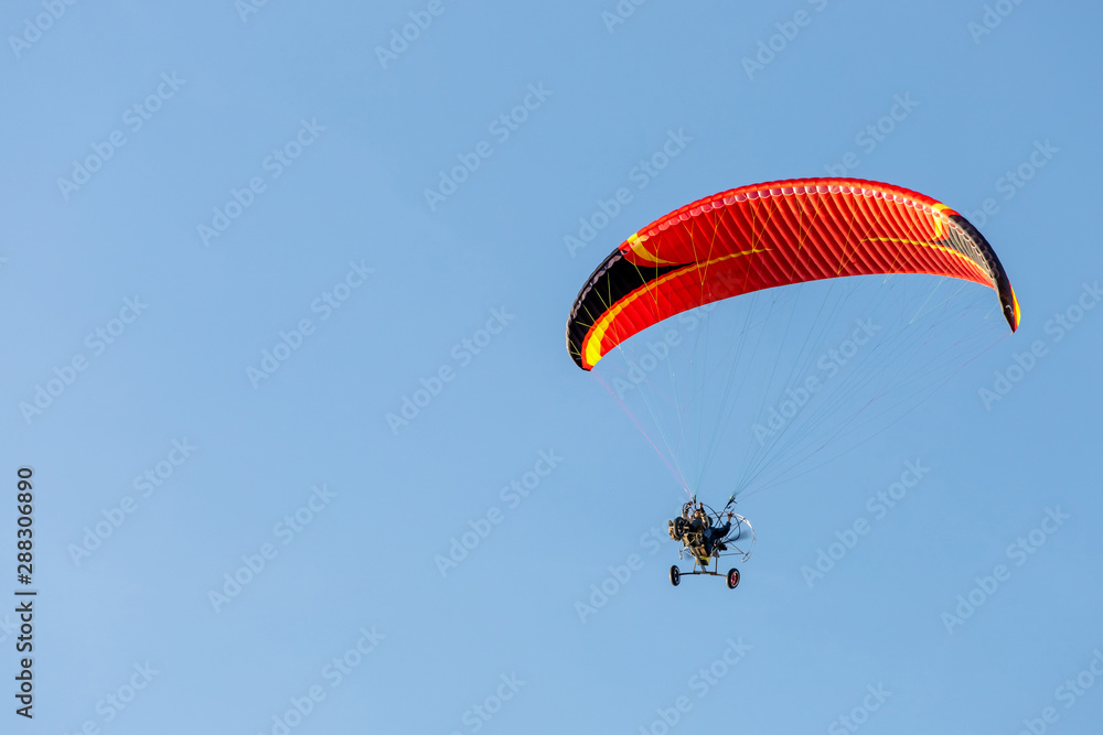 bright paraglider with a motor flies in the blue sky bright paraglider with a motor flies in the blue sky
