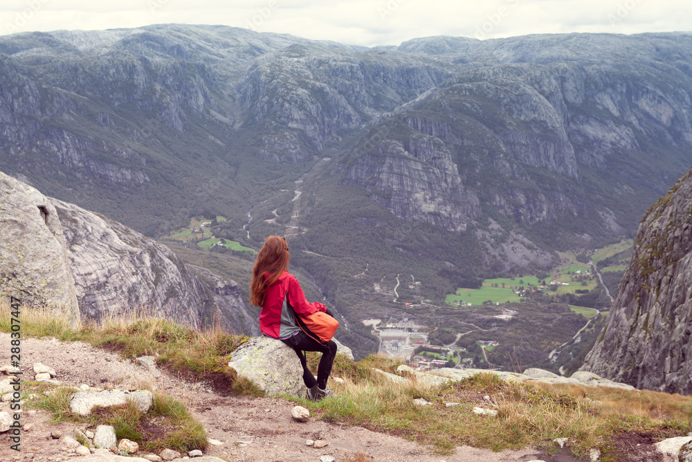 girl sitting on a stone and looking away the Norwegian mountains
