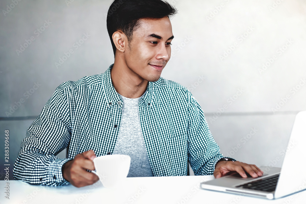 Happy Young Businessman Working on Computer Laptop in Office. Smiling and looking at Computer Happy Young Businessman Working on Computer Laptop in Office. Smiling and looking at Computer