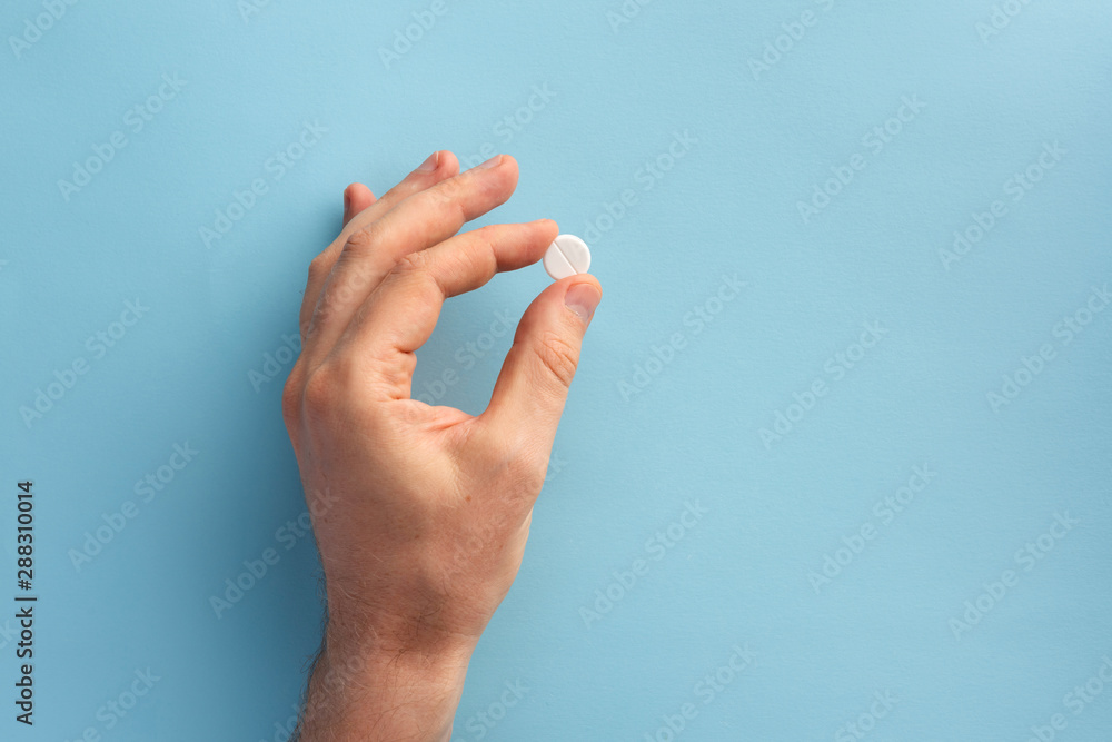 Naklejka premium Male hand holding one pill. Flat lay.
