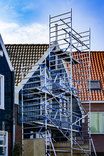 Scaffolding on a small brick house with wood paneling in Netherlands