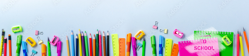 Notebook, colored pencils, ruler, pen, eraser, sharpener and more. School and office stationery on blue background. Banner Concept back to school. Top view.