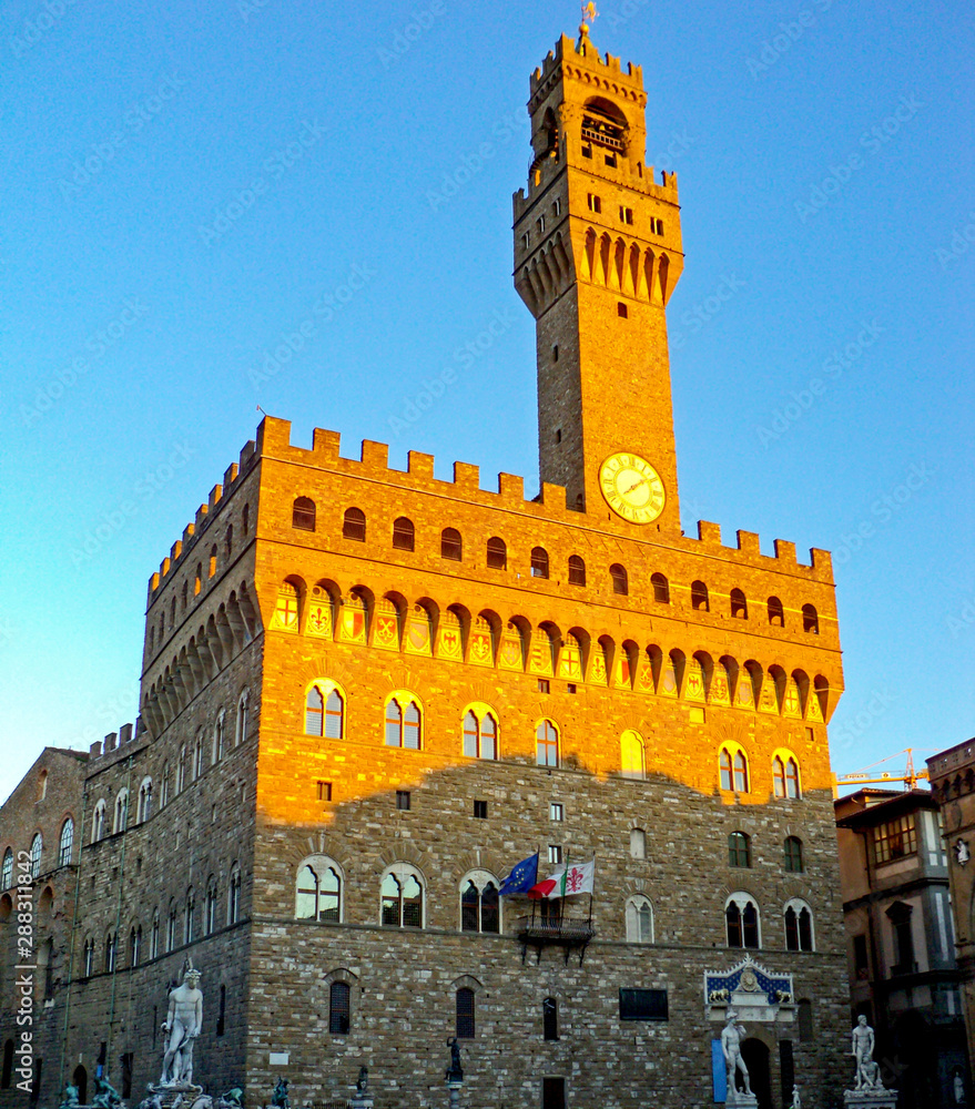 Obraz premium Palazzo Vecchio at piazza Della Signoria, Florence Italy. Famous historical building with bell tower with clock on blue sky background. Currently old Palace serves as a town hall.