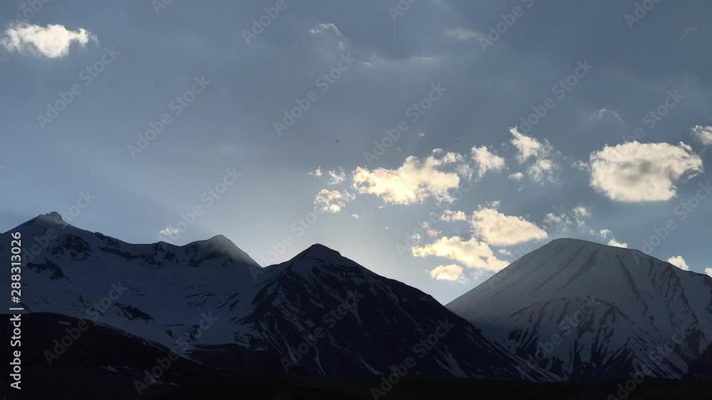 Time lapse clouds float across the blue sky over the snowy tops of the mountains on sunset, Georgia, Caucasus. Time lapse clouds float across the blue sky over the snowy tops of the mountains on sunset, Georgia, Caucasus.