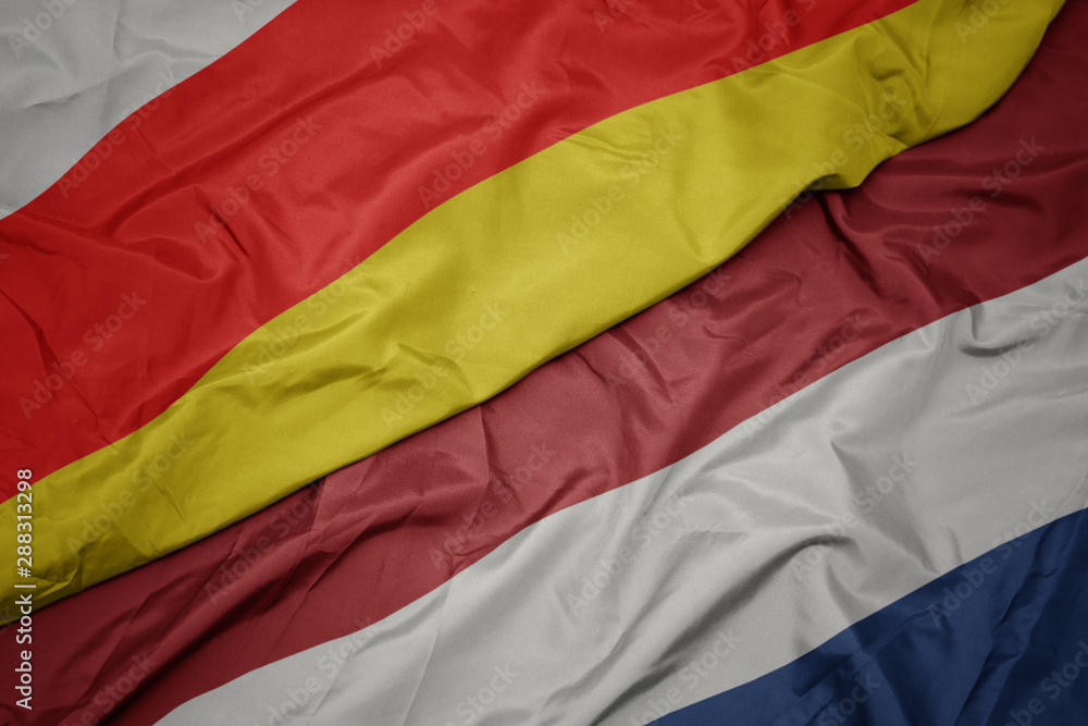 waving colorful flag of netherlands and national flag of south ossetia. waving colorful flag of netherlands and national flag of south ossetia.
