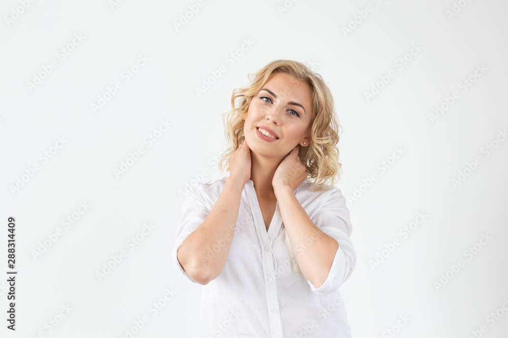 Cheerful young blond woman with long curly hair posing on a white background with copy space. The concept of a beautiful and well-groomed woman Cheerful young blond woman with long curly hair posing on a white background with copy space. The concept of a beautiful and well-groomed woman