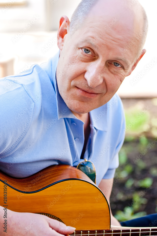 Middle-aged bald man plays guitar Middle-aged bald man plays guitar