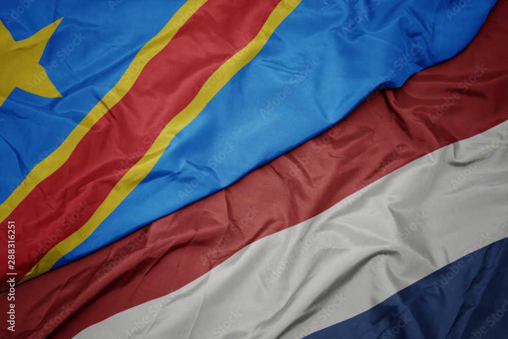 waving colorful flag of netherlands and national flag of democratic republic of the congo. waving colorful flag of netherlands and national flag of democratic republic of the congo.