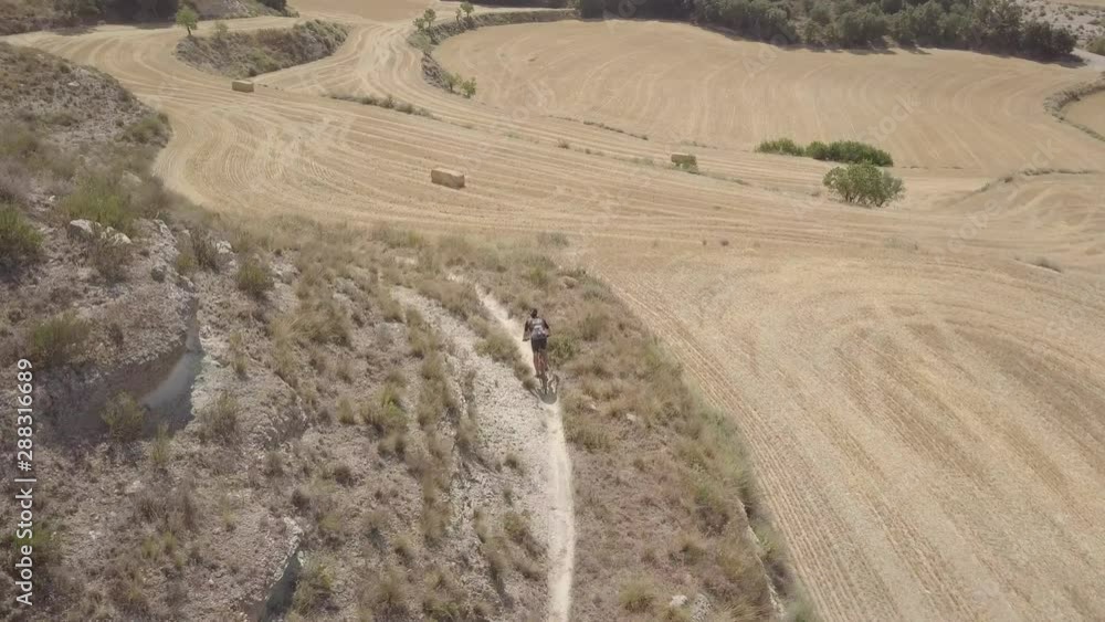 Aerial view of an athletic male speeding downhill on his mountain bike in a rural scene Aerial view of an athletic male speeding downhill on his mountain bike in a rural scene
