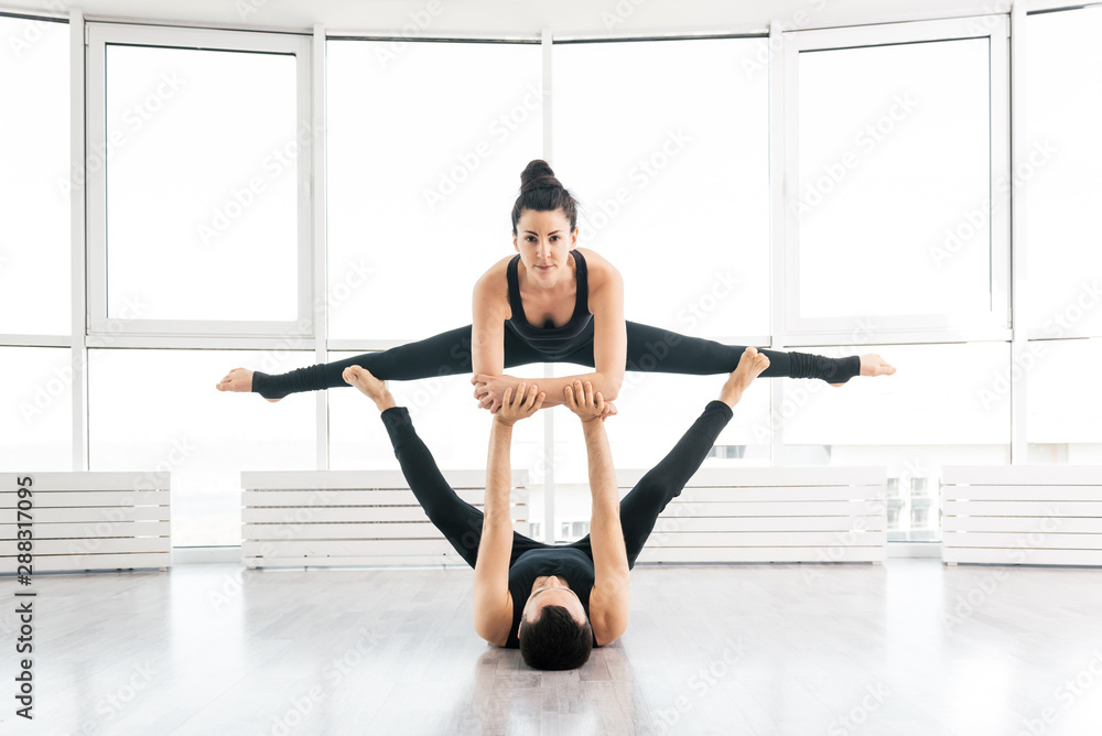 Obraz premium Young couple doing acro yoga in pair at studio
