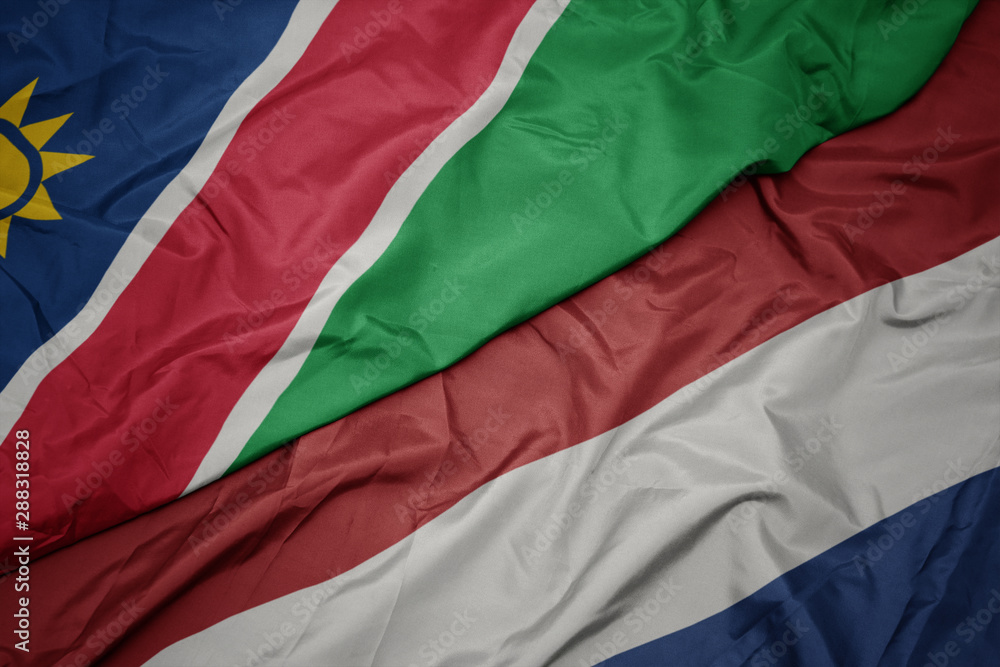 waving colorful flag of netherlands and national flag of namibia. waving colorful flag of netherlands and national flag of namibia.