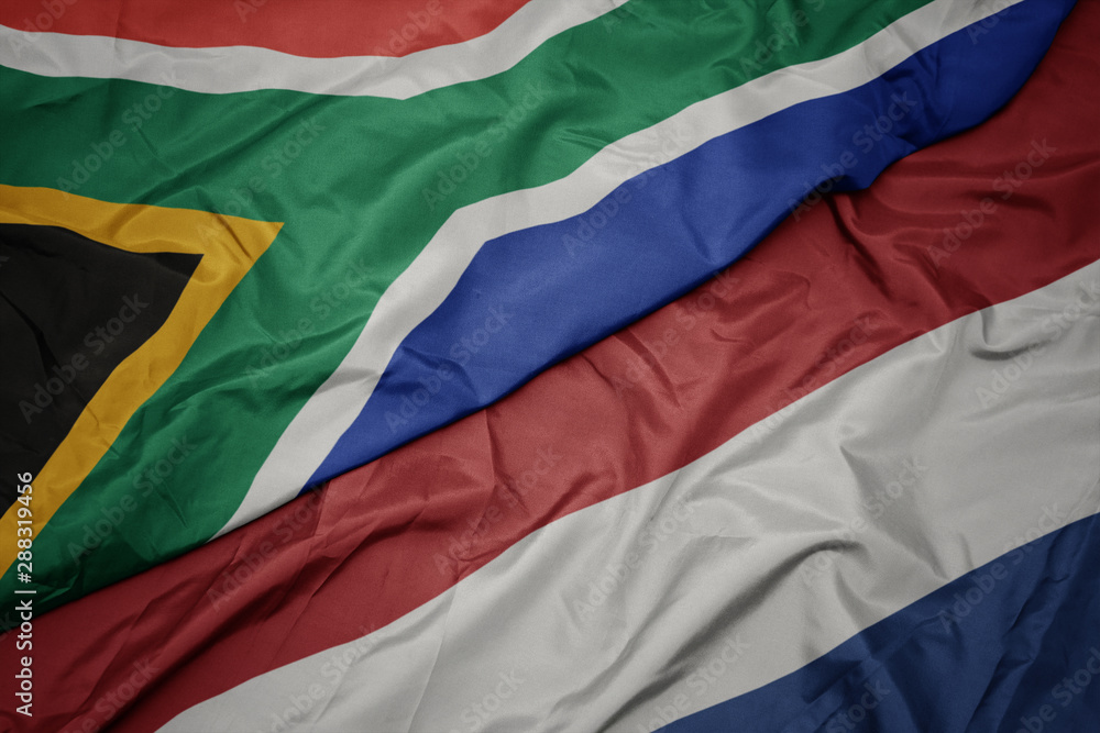 waving colorful flag of netherlands and national flag of south africa.