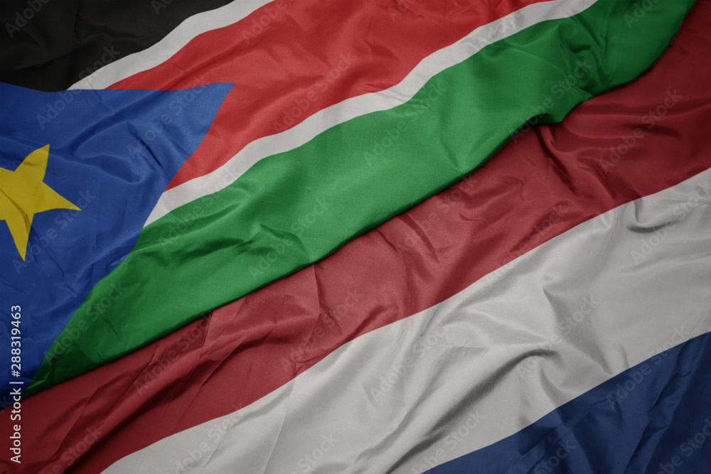 waving colorful flag of netherlands and national flag of south sudan.