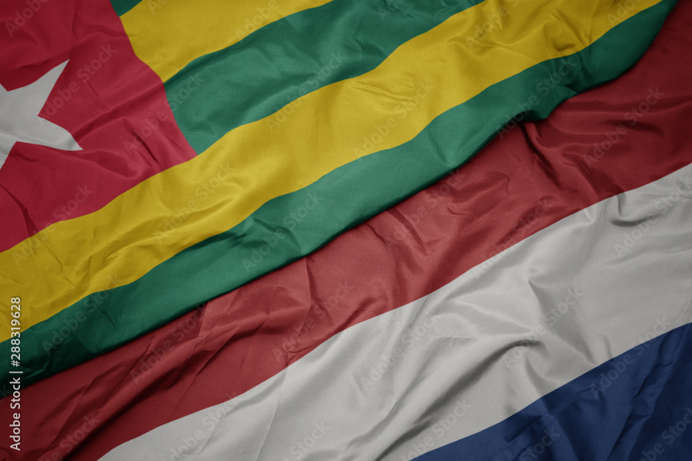 waving colorful flag of netherlands and national flag of togo. waving colorful flag of netherlands and national flag of togo.