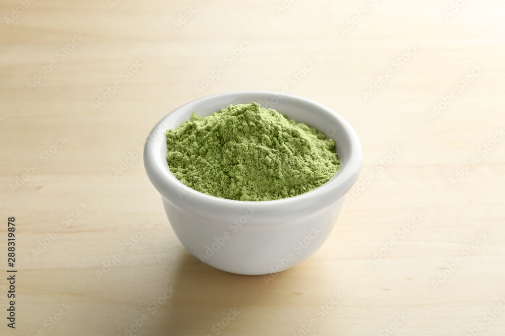 Bowl of wheat grass powder on wooden table Bowl of wheat grass powder on wooden table