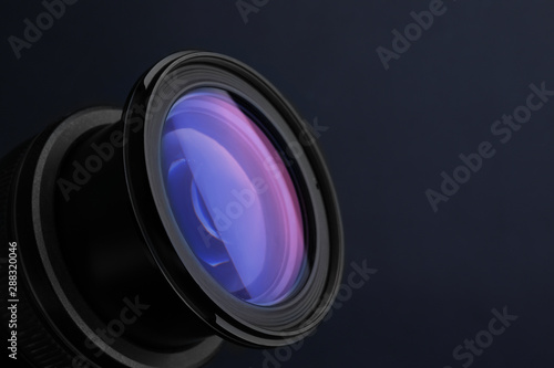 Lens of professional camera on dark blue background, closeup. Space for text