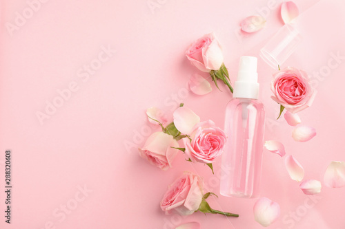 Fototapeta Naklejka Na Ścianę i Meble -  Flat lay composition with rose essential oil and flowers on pink background, space for text