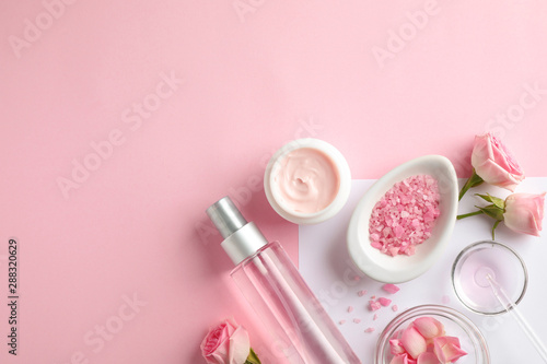 Flat lay composition with rose essential oil on color background, space for text