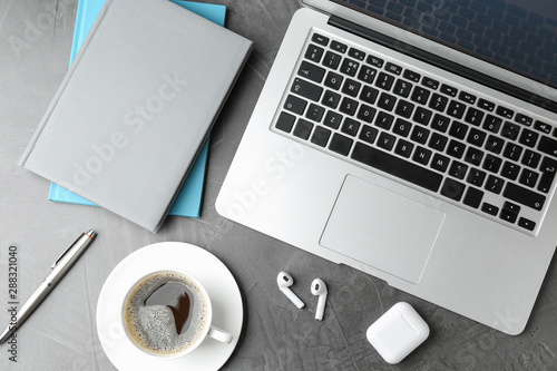 Flat lay composition with earphones and laptop on grey table