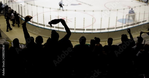 Silhouettes of wild fans jumping in a hockey stadium.