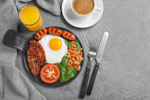 Delicious breakfast with fried egg served on grey table, flat lay. Space for text