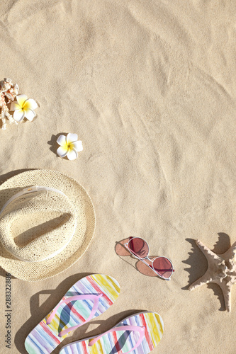 Flat lay composition with different beach accessories on sand. Space for text