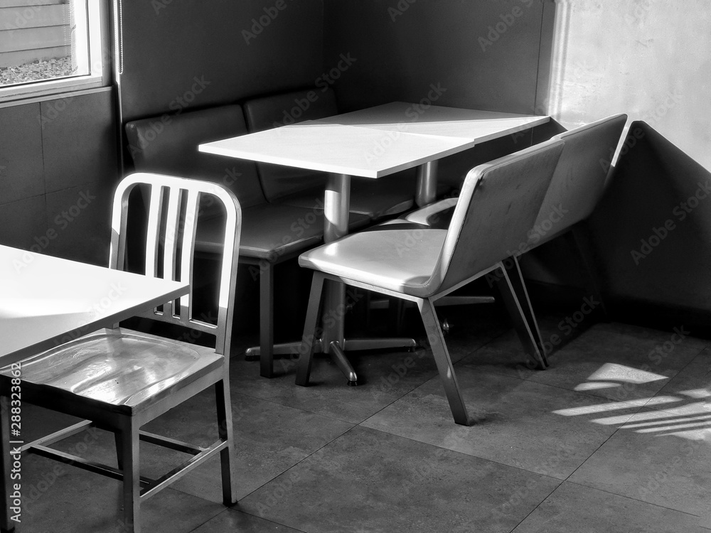 Chairs and table in the empty restaurant.The sun shines into the dining room. Sunlight hits objects.monochrome style.black and white color. Chairs and table in the empty restaurant.The sun shines into the dining room. Sunlight hits objects.monochrome style.black and white color.